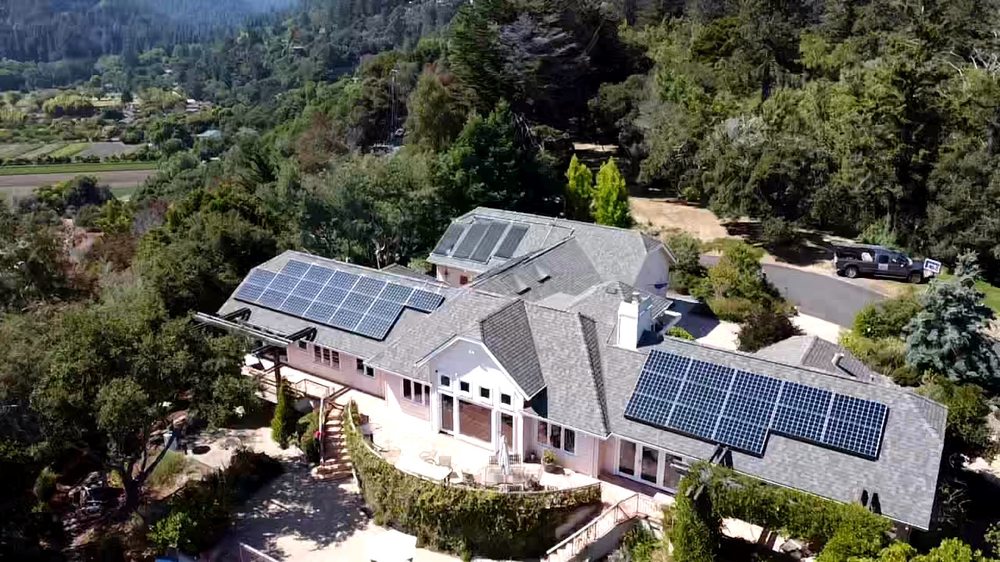 Aerial view of a Capitola, CA home with a new shingle roof and two solar panel arrays